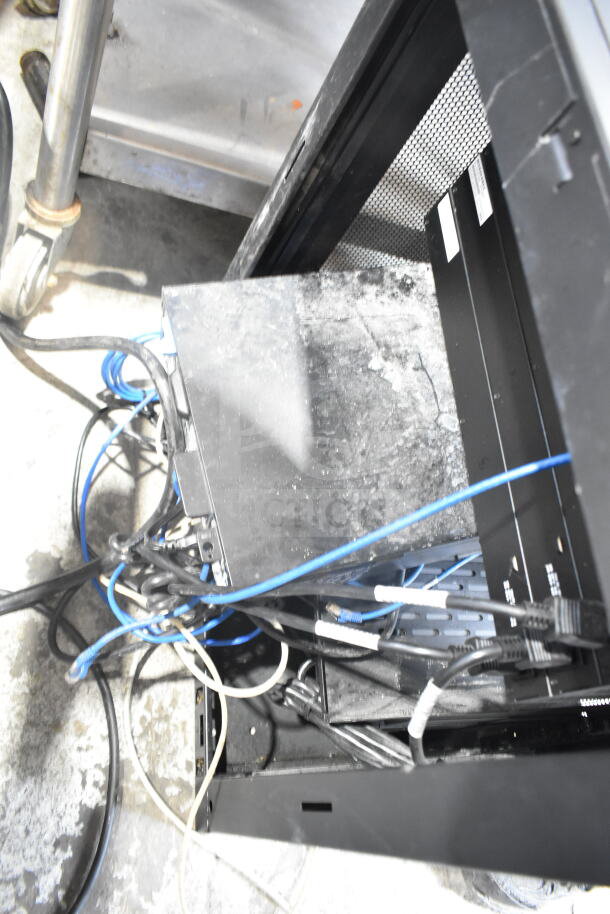 Tripp Lite AV Cabinet with contents, showing cables and electronic components inside. Dust visible, moderate wear.