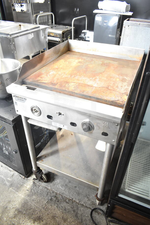 Jade Range countertop gas griddle with under shelf, used, visible rust on cooking surface, mounted on wheeled legs.