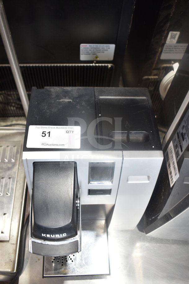 Keurig K150 single cup coffee machine, countertop model, 120V, with visible label "51 QTY" and PCI Auctions website.