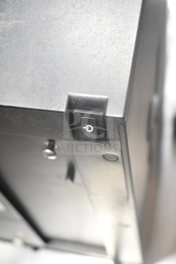 Close-up of a black Keurig K150 coffee machine showing the power switch. Model: K150, 120 Volts, 1 Phase.