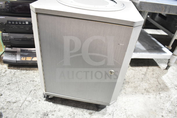 Chrome-finish speaker cabinet on casters with a locking door, showing minor surface wear.
