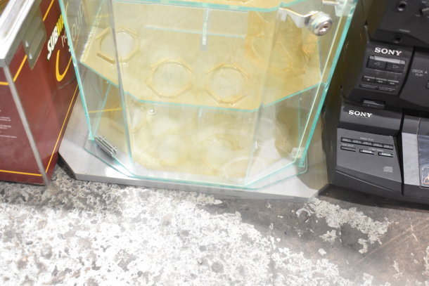 Acrylic display rack with glass panels and metal base, hexagonal shelves, in good condition. Suitable for retail use.