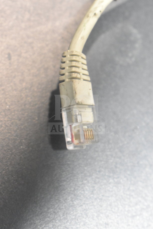 Close-up of a worn ethernet cable connector, part of an auction lot including 4 cash drawers and 3 Epson receipt printers.