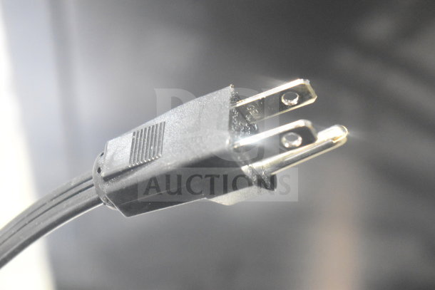 Close-up of a power plug from an Insinkerator hot water heater, featuring standard metal prongs.