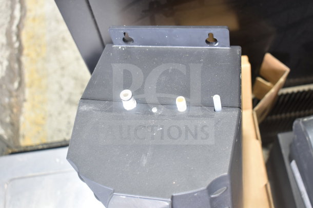 2 Insinkerator hot water heaters, black, wall-mountable, pipes visible, in good condition. Auction includes two units.