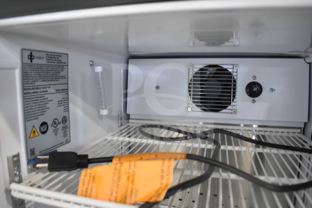 2024 QBD DC6LP-HC mini cooler merchandiser interior, showing wire shelves, fan, voltage label, and power cord.