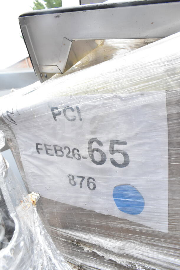 A pallet wrapped in plastic, labeled "FEB26-65" with various items, including cutting boards. Auction lot.
