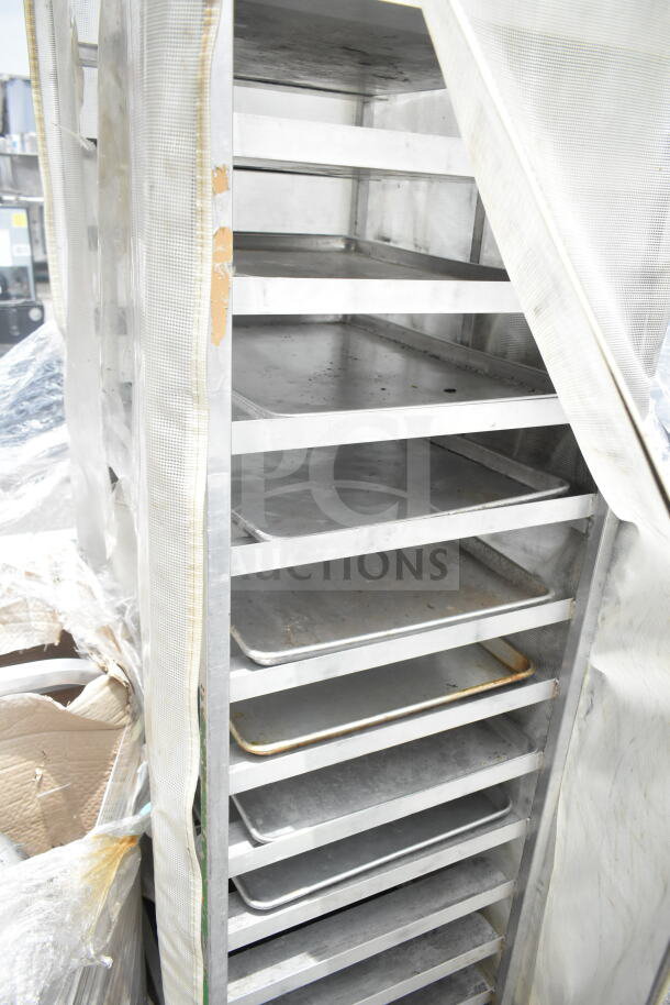 Commercial pan transport rack with multiple shelves, on commercial casters, covered with a protective sheet. Good condition.