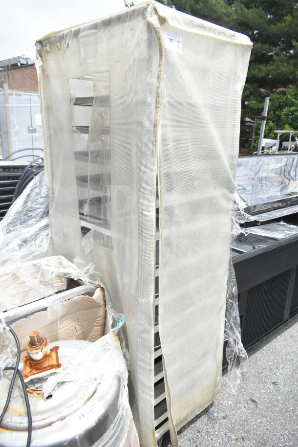 Commercial pan transport rack on casters with protective cover, shows some wear. Ideal for catering or bakery use.