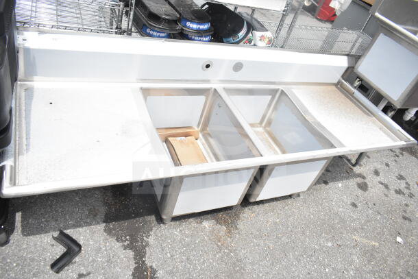 "Brand new Regency 600S21824224 commercial 2-bay sink, dual drain boards, minor scratches, stainless steel, ideal for kitchens."