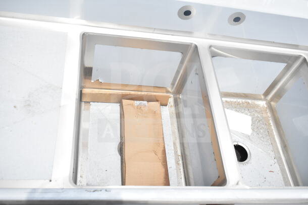 BRAND NEW SCRATCH AND DENT! Regency 600S21824224 Commercial 2 Bay Sink with dual drain boards; minor scratches visible.