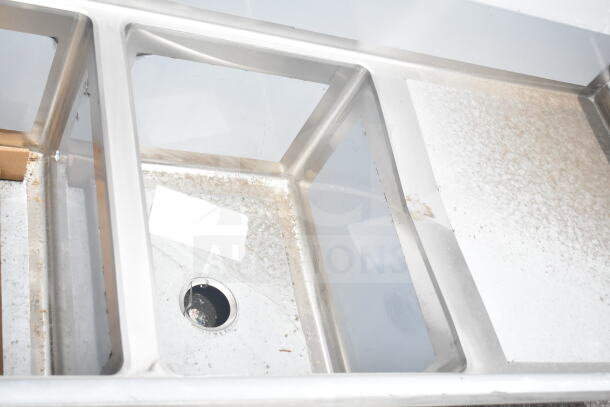 Brand new Regency 600S21824224 2 bay sink with dual drain boards, showing scratches and dents. Stainless steel finish.