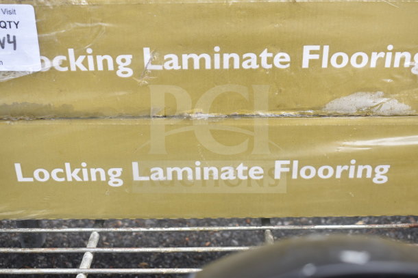 Locking laminate flooring boxes on a cart, visible labels, minor wear. Auction includes soap dispensers.