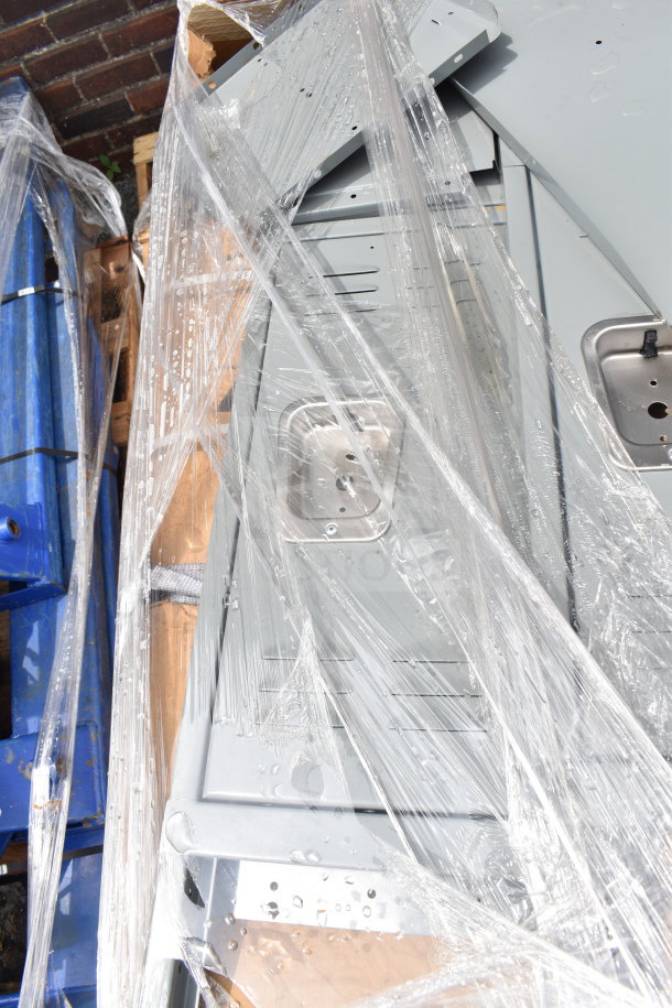 Pallet of scratch and dent gray metal lockers, brand new, partially unpacked with protective wrap. Visible dings.