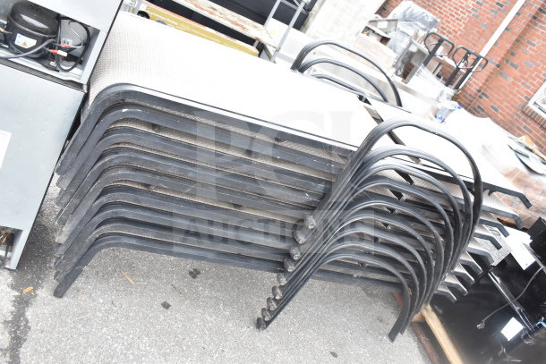 Stack of nine outdoor chaise lounge chairs with black metal frames, seen in used condition, ideal for bulk purchase.