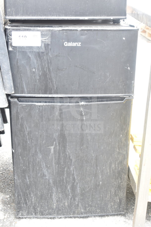Galanz GL31BKE mini cooler with freezer, visible scratches, black finish, 120 volts, 1 phase, auction label attached.