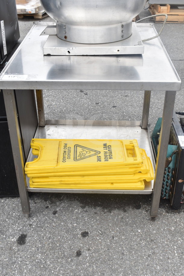 Stainless steel commercial table with under shelf, holds stacked yellow "Caution Wet Floor" signs, in good condition.