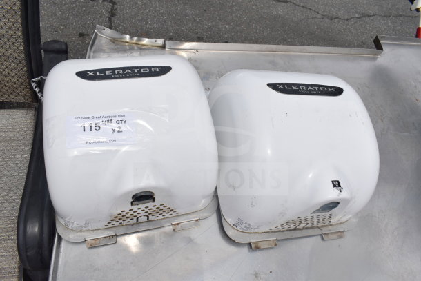 Two Xlerator hand dryers in used condition, white, labels indicating model and auction details visible.