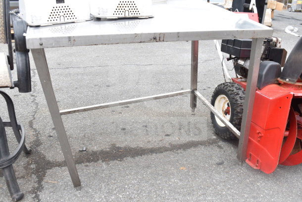 Metal table with a rectangular top and sturdy legs, used condition. Signs of wear and some rust visible on the frame.
