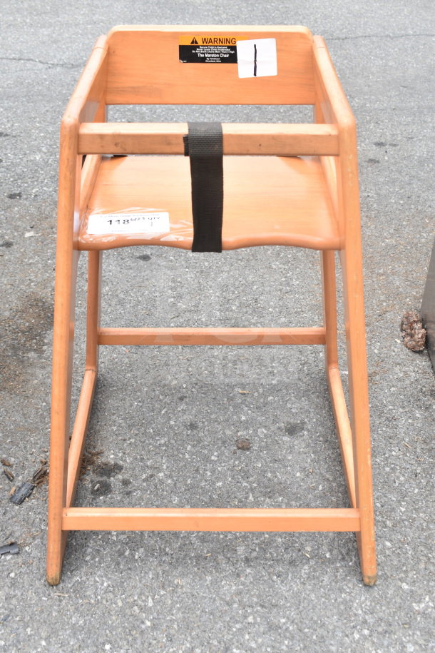 Wooden high chair with natural finish, safety strap, and visible warning label. Good condition with minor wear.