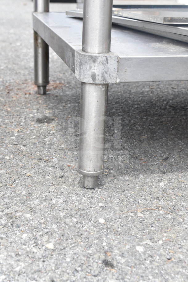 Stainless steel commercial table with sink bay, over shelf, and under shelf. Features sturdy legs; condition shows wear.