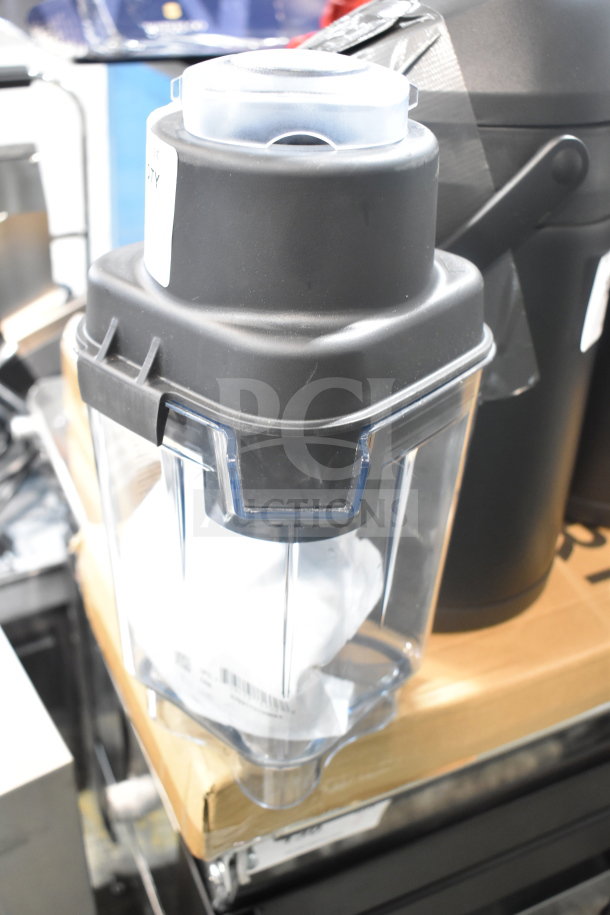 Brand new Blendtec blender pitcher, scratch and dent condition, clear plastic with black lid, boxed packaging.