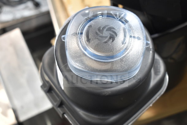 New Blendtec blender pitcher, scratch and dent condition; clear lid with Blendtec logo visible.