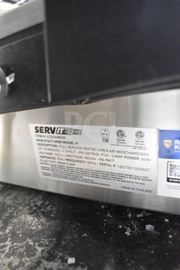 Brand new ServIt 423OAM65D 24" heated display merchandiser with 2 slanted shelves. Label shows 120V, 1800W, IPX4. Made in Thailand.