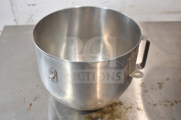 Stainless steel mixing bowl with handle attachment for a mixer. Slight wear visible. Part of a set including whisk attachment.