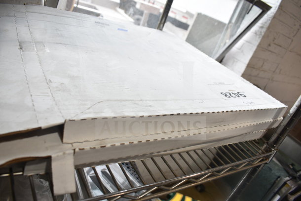 Stacked white boxes containing Lavex 598AVG17GN green scrubbing pads and Norton Q421 floor screen discs on a metal shelf.