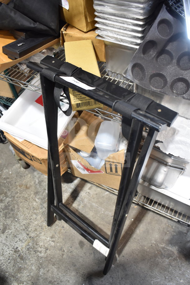 Black metal serving tray stand with foldable legs, visible in storage area. Condition appears used with minor wear.