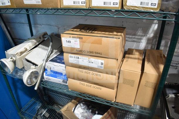 Boxes of assorted items including a DualLite exit sign and Cooper LED outdoor emergency light on a metal shelf. Auction lot 149.