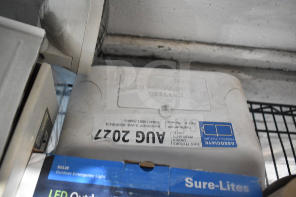 Assorted auction items including DualLite Exit Sign and Cooper LED Outdoor Emergency Light. Minor wear visible.