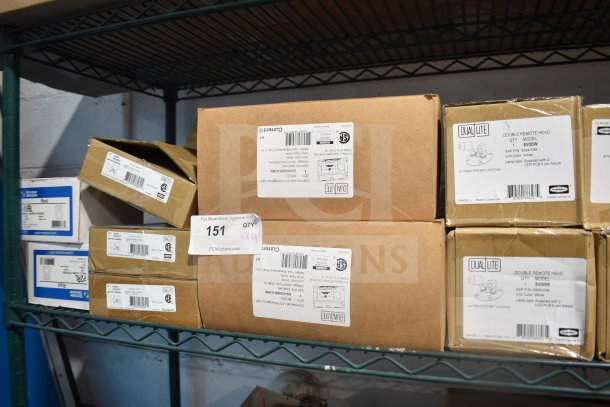 Boxes of DualLite lighting items, including Double Remote Heads and LED Emergency Lights, stacked on a shelf.