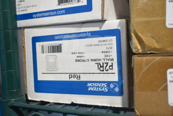 Cardboard boxes of System Sensor P2RL wall horn strobes on a shelf; model and barcode visible.