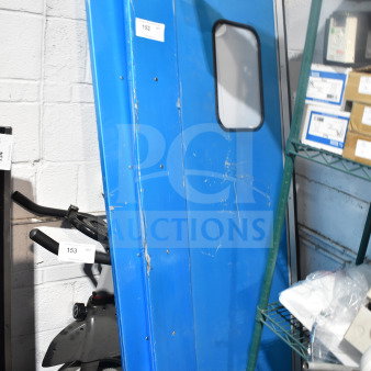 Two blue kitchen traffic doors with small windows, showing surface wear and marks. Tags display number 152, indicating auction lot.