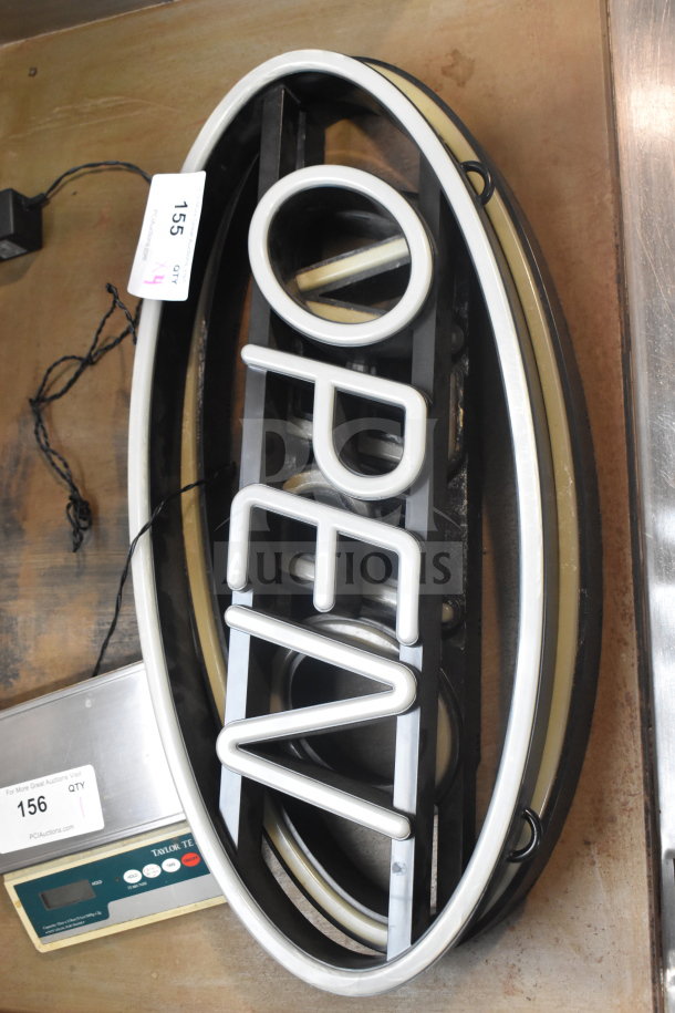 Oval-shaped "OPEN" neon sign, white lettering on black frame, good condition, includes power cord. Auction tag indicates 4x bid.