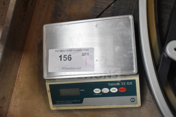 Taylor TE32R Countertop Scale with digital display, stainless steel platform, and control buttons. Display shows "156".