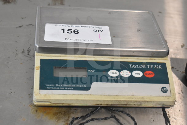 Taylor TE32R countertop scale, stainless top, digital display, buttons for hold, tare, on/off. Capacity 32oz/1000g.