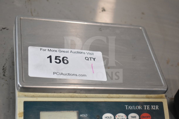 Taylor TE32R countertop scale, stainless steel, digital display, fair condition. Auction tag reads "156" with PCI Auctions website.