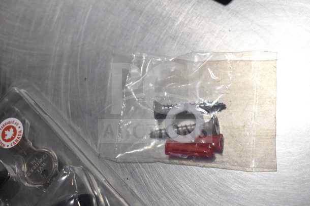 10 various hardware items, including screws, washers, and a key in plastic packaging. Some are marked "Made in Canada."
