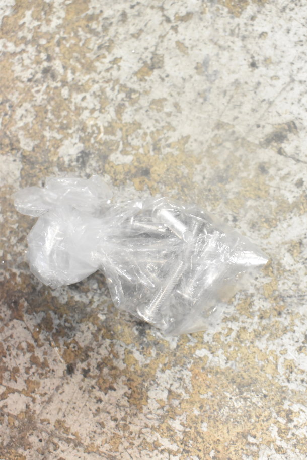 A bag of metal screws on a textured surface, wrapped in clear plastic.