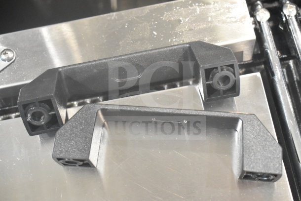 Black plastic handles for Avantco 177PG400T Panini Grill on stainless steel surface, showcasing detail and condition.