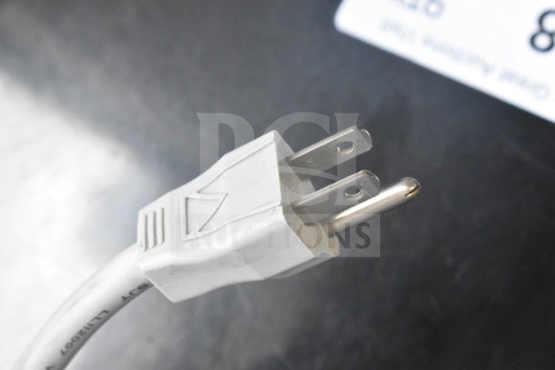 A white power plug with visible prongs, attached to a cord, on a dark surface.