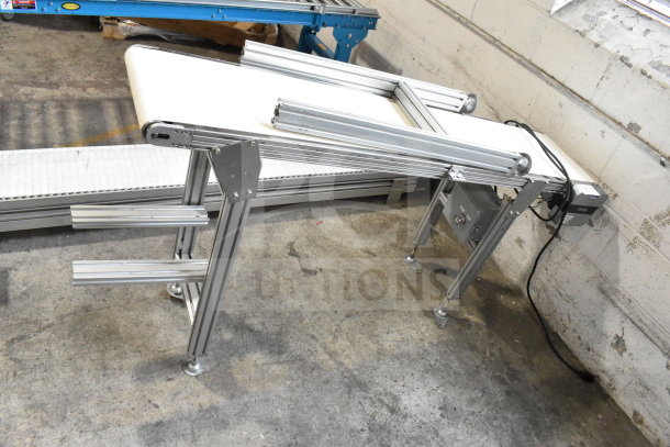 MiSumi floor-style conveyor, 115V, 1 phase, in excellent condition. Features aluminum frame and white belt.