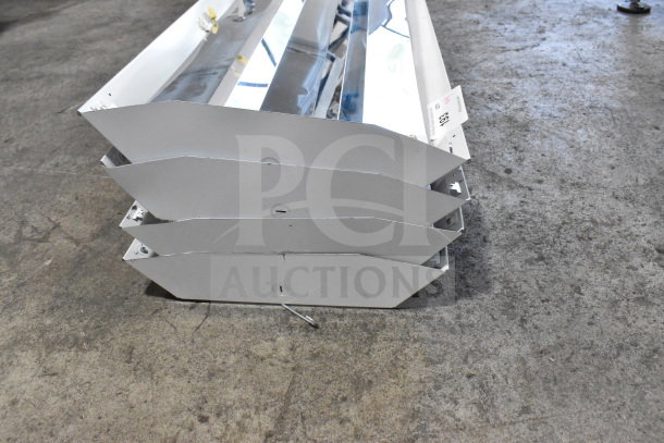 Four Howard M032817 light fixtures stacked, metallic finish, new condition. Auction tag showing item number visible.