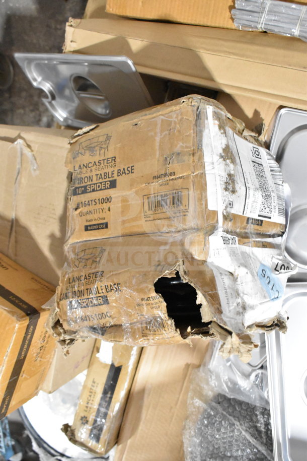 Damaged box of Lancaster cast iron table base with visible labels and contents, amidst various other unpackaged items.