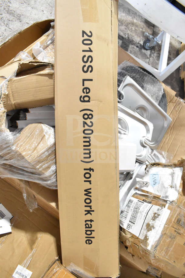 Box with 201SS work table leg (820mm) amid various mixed items, including pans and exit sign, slightly damaged packaging.