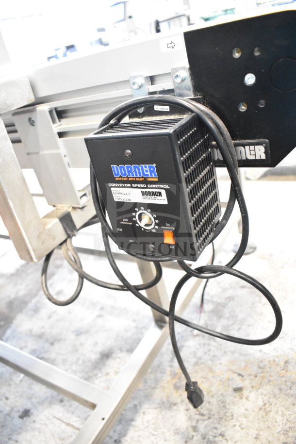 Dorner 32MTEM12 floor style conveyor with speed control box, 115 volts, 1 phase, attached to metal table.