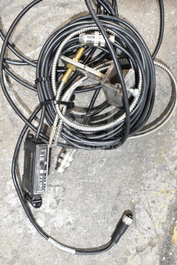 Tangled cables including a fiber optic light guide, I/O breakout cable, and a device marked "video out." Worn condition.